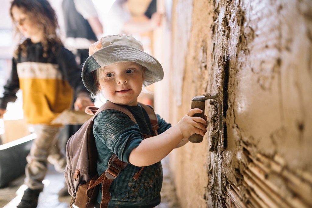 Kind verputzt Lehmwand